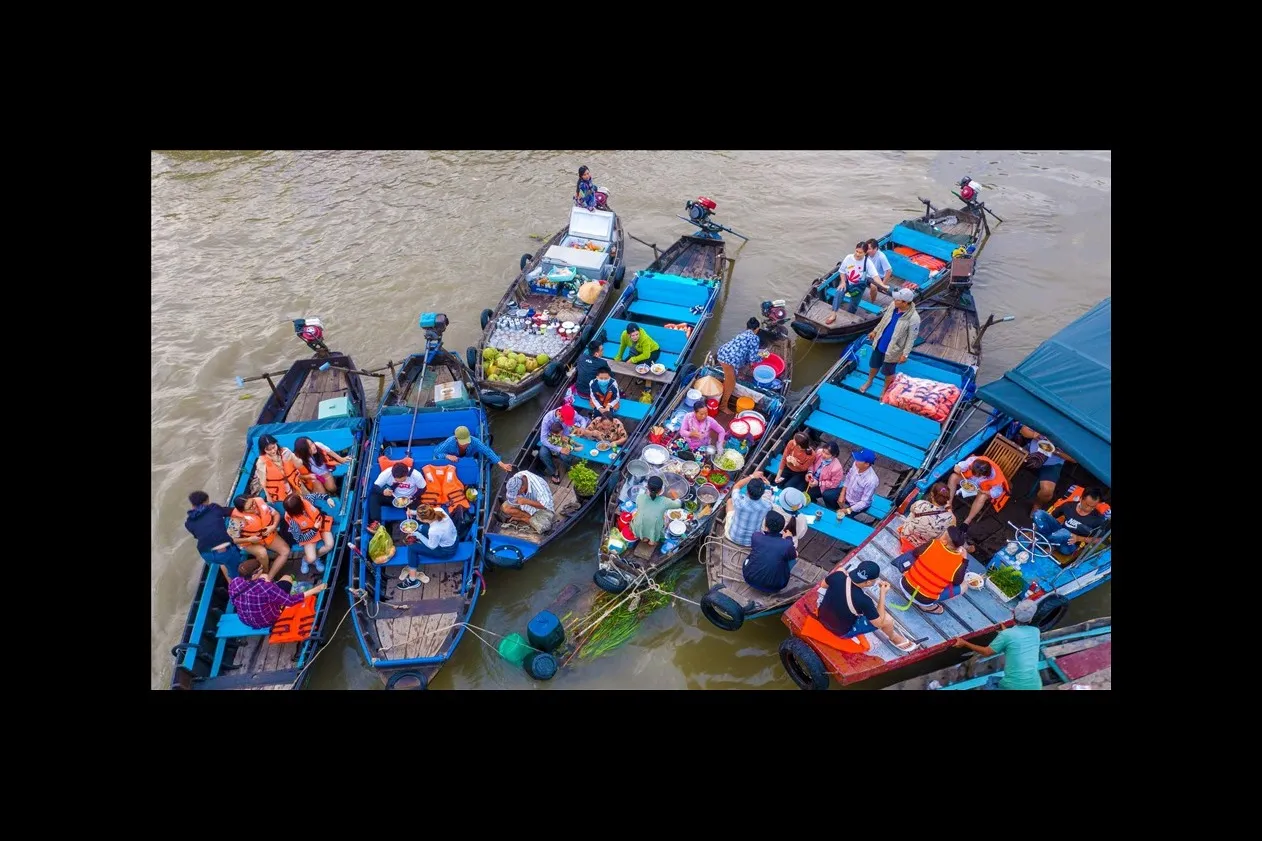 Turisti americani comprano frutta e mangiano hủ tiếu sulle barche del mercato galleggiante
